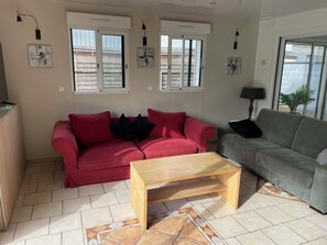 A living room with two sofas, a wooden coffee table, and a tiled floor.