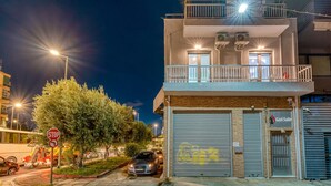 A building with a garage door, a stop sign, and a tree in front. - Gazi Suite With Private Rooftop (Athina)