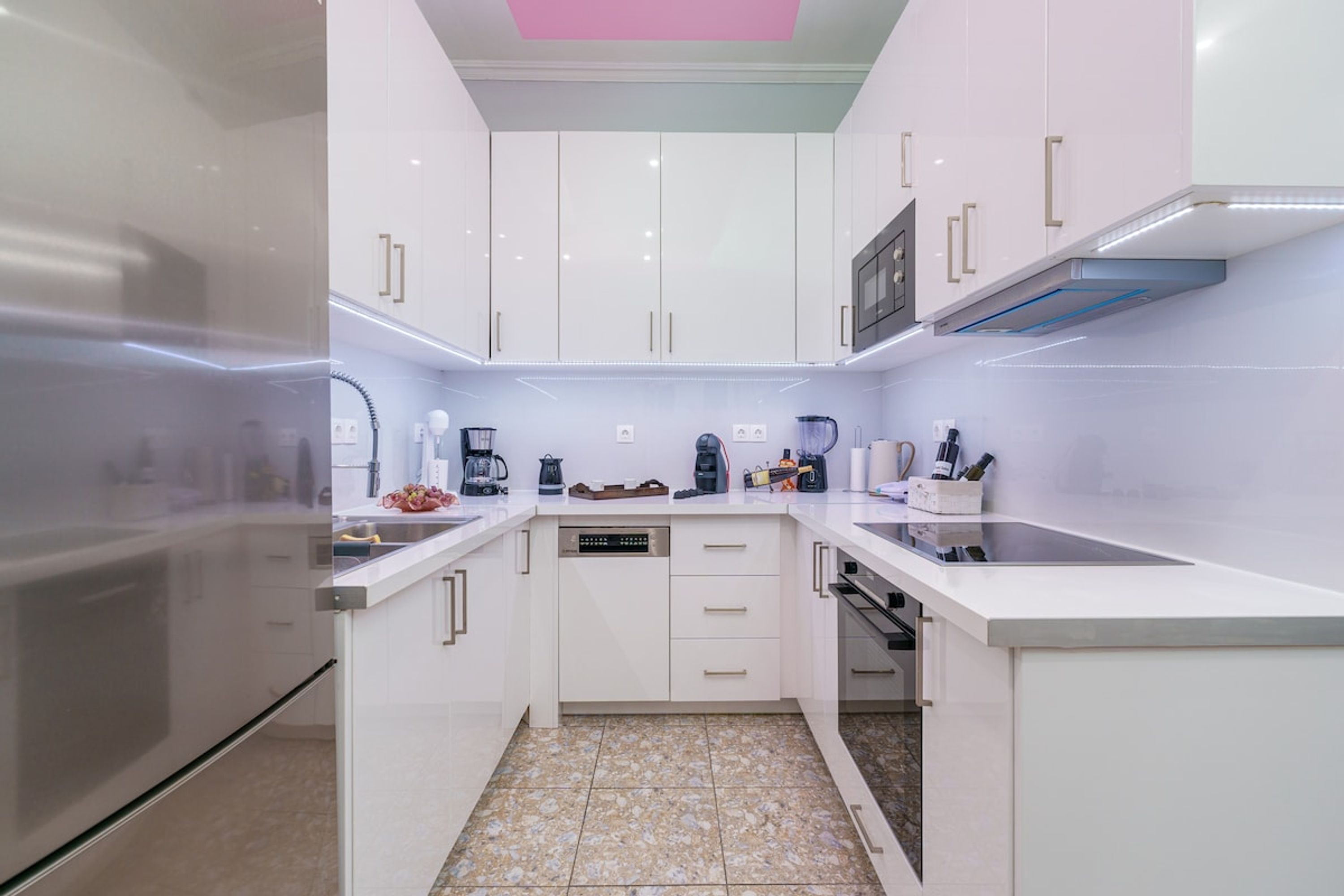 Una cocina moderna con armarios blancos, un refrigerador de acero inoxidable y un lavavajillas empotrado.