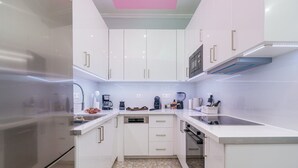 A modern kitchen with white cabinets, a stainless steel refrigerator, and a built-in dishwasher. - Gazi Suite With Private Rooftop (Athina)