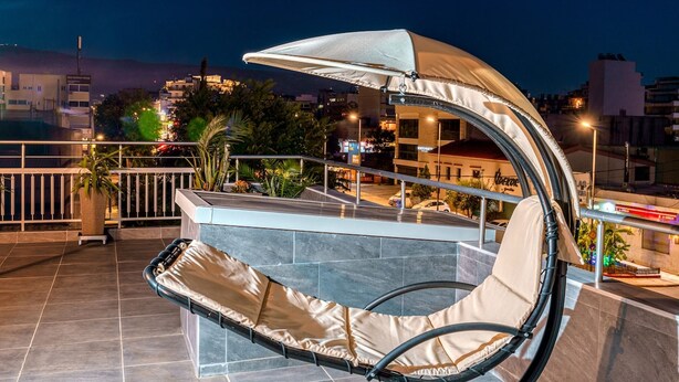 A rooftop terrace with a cushioned seating area, a canopy, and a view of the cityscape at night. - Gazi Suite With Private Rooftop (Athina)