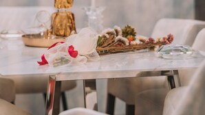 A dining table with a candle, a glass decanter, and a decorative arrangement. - Gazi Suite With Private Rooftop (Athina)