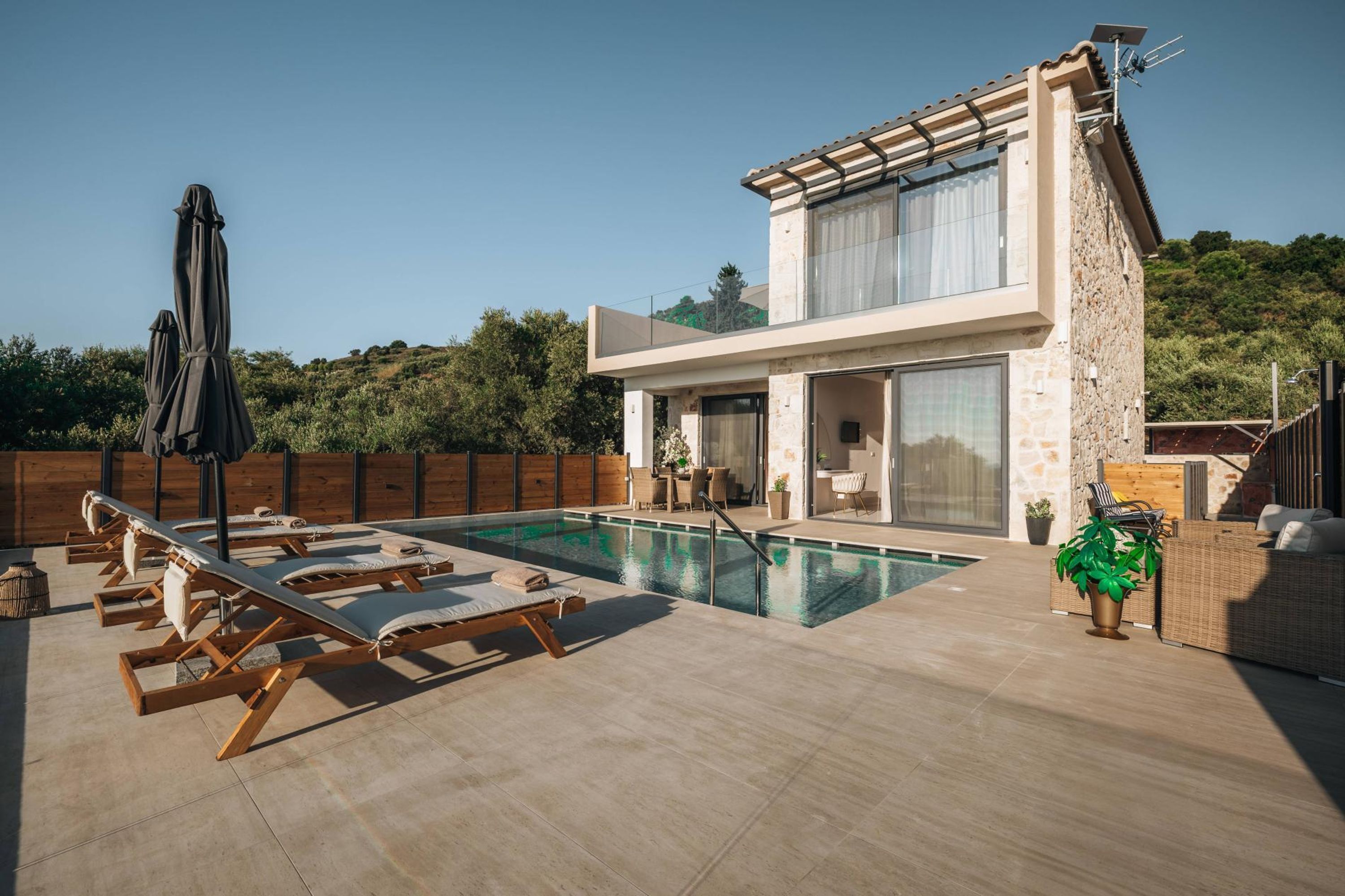A modern villa with a swimming pool, outdoor seating, and a stone facade.