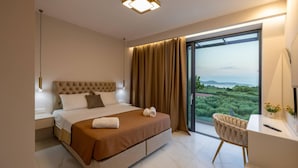 A modern bedroom with a large bed, a desk, and a view of greenery through the window. - J&K Villa with private pool (Zakynthos)