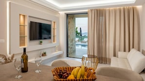 A modern living room with a flat-screen TV, a wine bottle, and a fruit basket. - J&K Villa with private pool (Zakynthos)