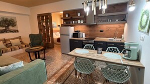 A compact living space with a kitchenette, a dining area with a table and chairs, a sofa, and a chair. - Athenian Stay 301 By VPN (Athens)