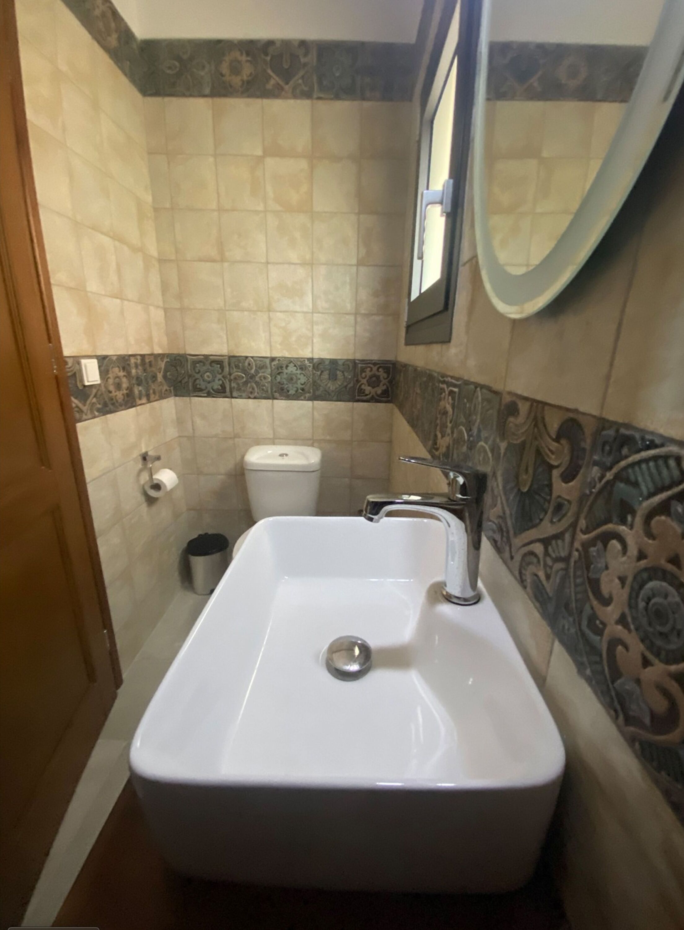 Un baño con un lavamanos blanco, inodoro y espejo.