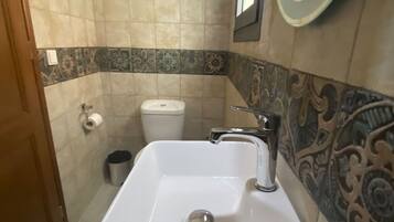 Un baño con un lavamanos blanco, inodoro y espejo.