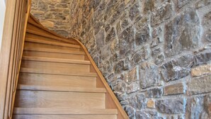Una scala in legno con un muro in pietra su un lato.
