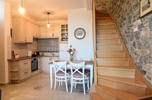 Une cuisine avec des meubles en bois, une table à manger avec des chaises et un escalier en pierre.