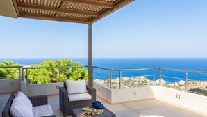 A balcony with wicker furniture, a view of the sea, and a clear sky. - Luxury Villa Hara with private pool (Malevizi)