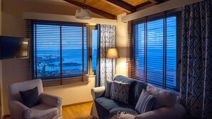 A living room with a sofa, armchair, and a TV mounted on the wall. - Luxury Villa Hara with private pool (Malevizi)