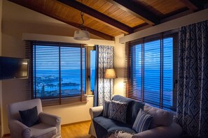 A living room with a sofa, armchair, and a TV mounted on the wall. - Luxury Villa Hara with private pool (Malevizi)