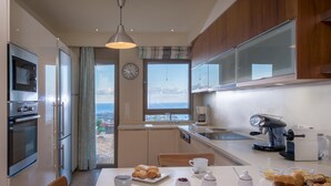 A modern kitchen with a dining area, a coffee machine, and a view of the sea. - Luxury Villa Hara with private pool (Malevizi)
