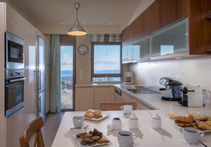 A modern kitchen with a dining area, a coffee machine, and a view of the sea. - Luxury Villa Hara with private pool (Malevizi)