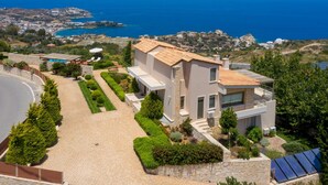 A modern two-story house with a paved driveway, a well-maintained garden, and solar panels. - Luxury Villa Hara with private pool (Malevizi)