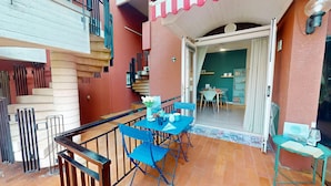 A balcony with blue chairs and a table, a staircase, and a view into a dining area. - Sirmio Green Shore By Bookinggardalake (Sirmione)