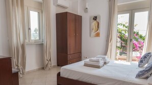 A bedroom with a bed, a wardrobe, a painting, and a window with curtains. - Villa Rafaella in Rethymno (Rethymno)