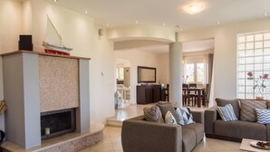 A modern living room with a fireplace, two sofas, and a dining area in the background. - Villa Rafaella in Rethymno (Rethymno)