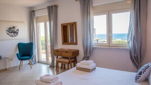 A hotel room with a bed, a desk, a chair, and a view of the sea. - Villa Rafaella in Rethymno (Rethymno)