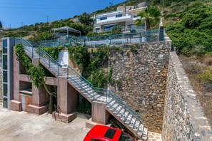 A modern building with a stone retaining wall and a metal staircase. - Elounda Senses Luxury villa with private pool (Agios Nikolaos Municipality)