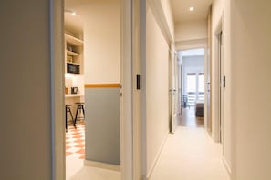 A hallway with a checkered floor, leading to a kitchen area with a microwave and shelves. - Acropolis Luxury retreat (Athens)