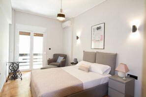 A bedroom with a bed, a chair, a table, and a nightstand. - Acropolis Luxury retreat (Athens)