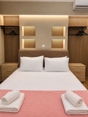 A hotel room with a large bed, two bedside tables, a wall-mounted air conditioner, and a wooden slat wall design. - Monastiraki 110 @SuperHost Hub (Athens)