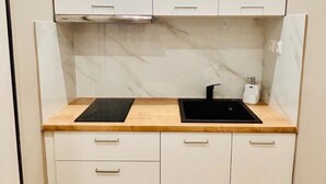 A compact kitchen with white cabinets, two black countertops, a sink, and a marble backsplash. - Monastiraki 110 @SuperHost Hub (Athens)
