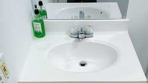 A white bathroom sink with a mirror above it, a faucet, and two bottles of hand soap. - 2-bedrooms next to Grace Bay (Grace Bay)
