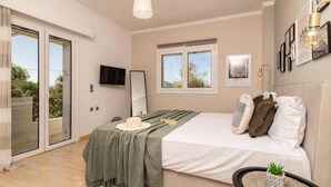 Ein Schlafzimmer mit Bett, Fernseher, Fenster und Balkon.