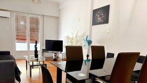 A modern living room with a glass dining table, black chairs, a sofa, and a TV. - Modern Apartment in Athens Center (Athina)