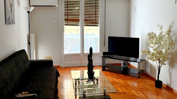 A living room with a sofa, coffee table, TV, and a cactus plant. - Modern Apartment in Athens Center (Athina)
