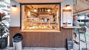 Ein kleiner Imbissstand mit Speisekarte, Mülleimer und Holztresen.