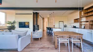 Ein modernes Wohnzimmer mit einer Couch, einem Esstisch mit Stühlen, einem Fernseher und einem Kamin.