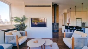 Ein modernes Wohnzimmer mit Kamin, bequemen Sitzgelegenheiten und Blick auf die Stadt.