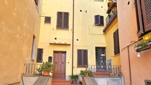 A narrow street with terracotta steps leading to a yellow building with multiple windows and shutters. - Renovated flat with panoramic view-Casa Olivazzo (Chiusi)