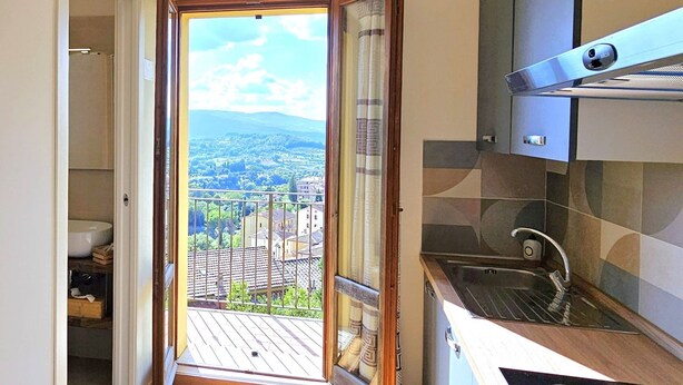 A narrow kitchen with a view of a cityscape through an open door. - Renovated flat with panoramic view-Casa Olivazzo (Chiusi)