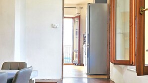 A compact kitchen with a dining table and chairs, a refrigerator, and a wooden bench. - Renovated flat with panoramic view-Casa Olivazzo (Chiusi)