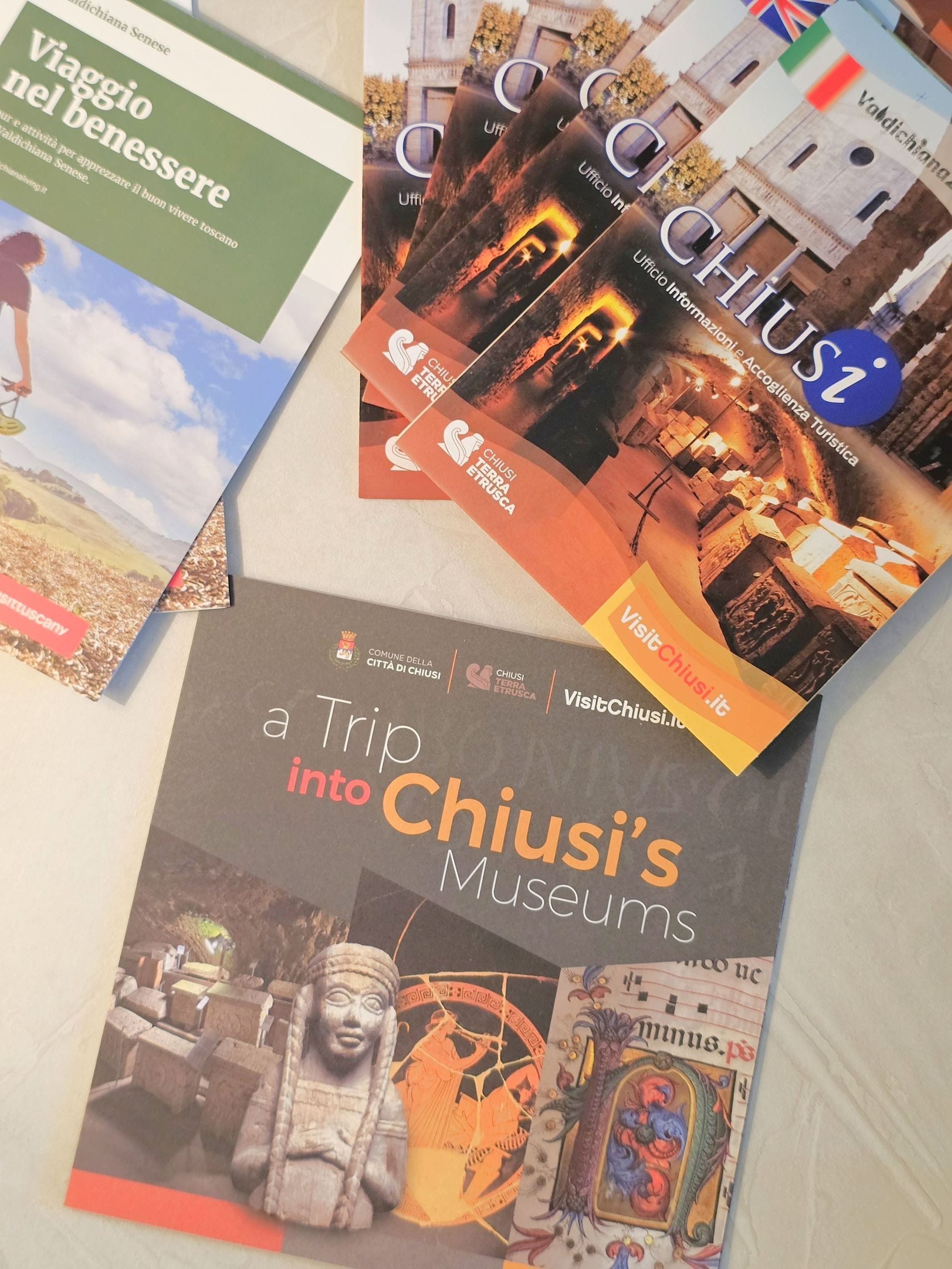 Una colección de folletos turísticos de los museos de Chiusi, incluyendo 'VisitChiusi.it' y 'Ufficio Informazioni Accoglienza Turistica'.