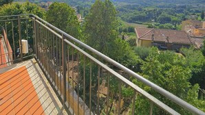 A balcony with a metal railing overlooking a scenic landscape with buildings and mountains in the distance. - Renovated flat with panoramic view-Casa Olivazzo (Chiusi)