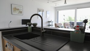 Eine Küche mit einem schwarzen Spülbecken, einem Wasserhahn und einem grünen Utensilienhalter auf der Arbeitsfläche.