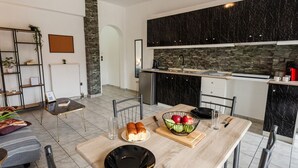 Ett modernt kök med en väggbeklädnad av sten, ett matbord med stolar och en liten sittgrupp med en soffa och ett soffbord.