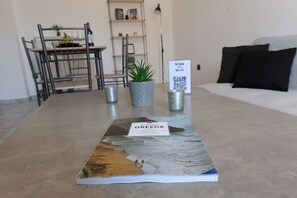 Ein Wohnzimmer mit Couch, Bücherregal, Tisch, Topfpflanze und einem Schild mit einem QR-Code.