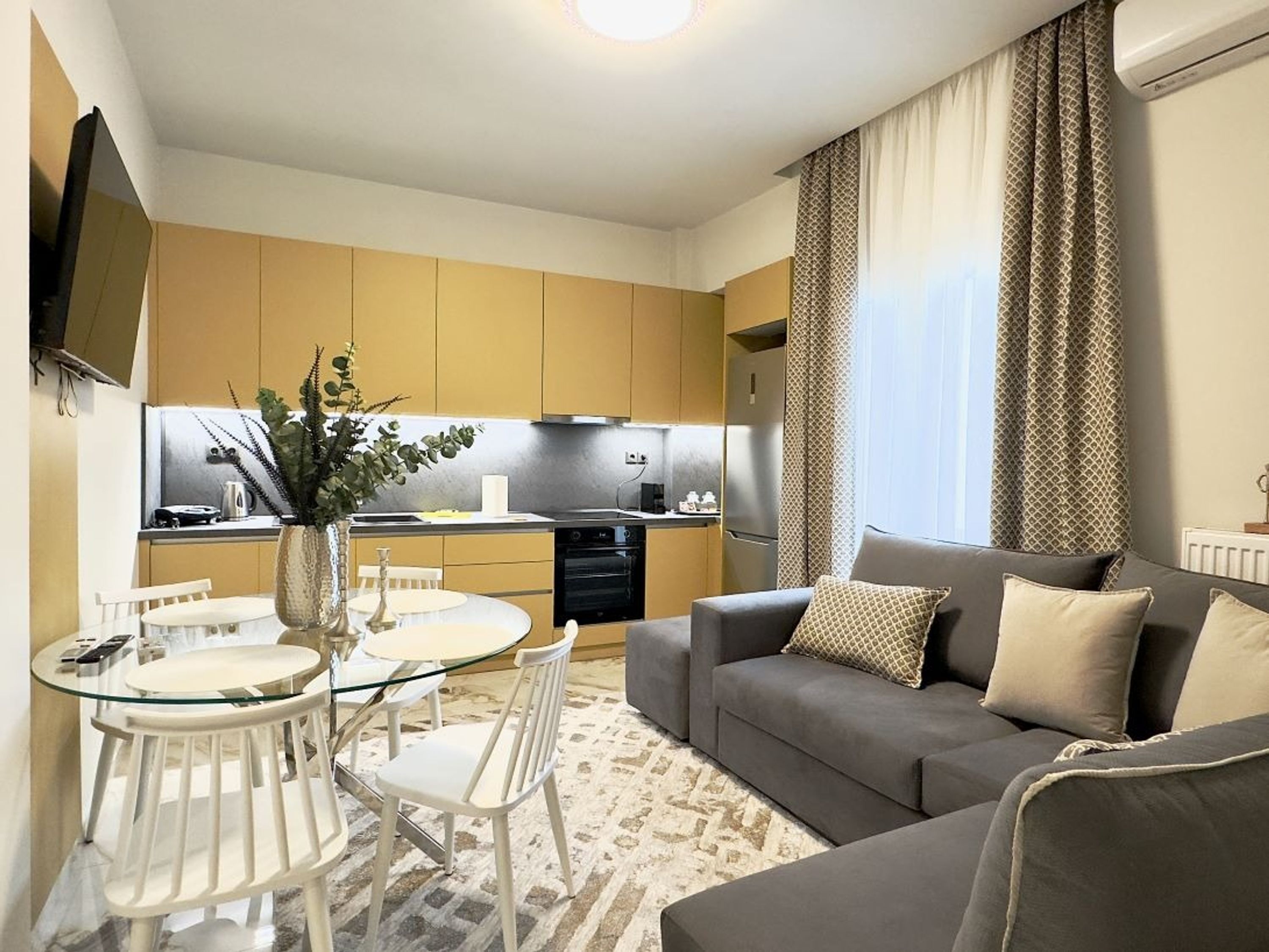 A compact living space with a dining area, kitchenette, and a sofa.