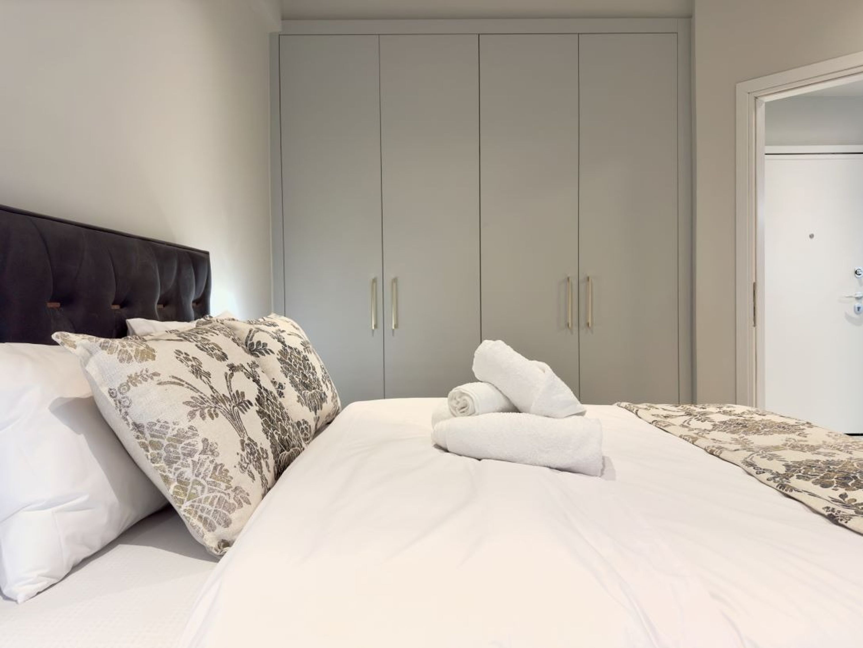 Een slaapkamer met een bed, twee kussens, een hoofdbord, een kledingkast en een deur.