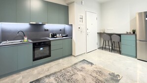 Cozinha moderna com armários verde-água, eletrodomésticos de aço inoxidável e um tapete estampado.