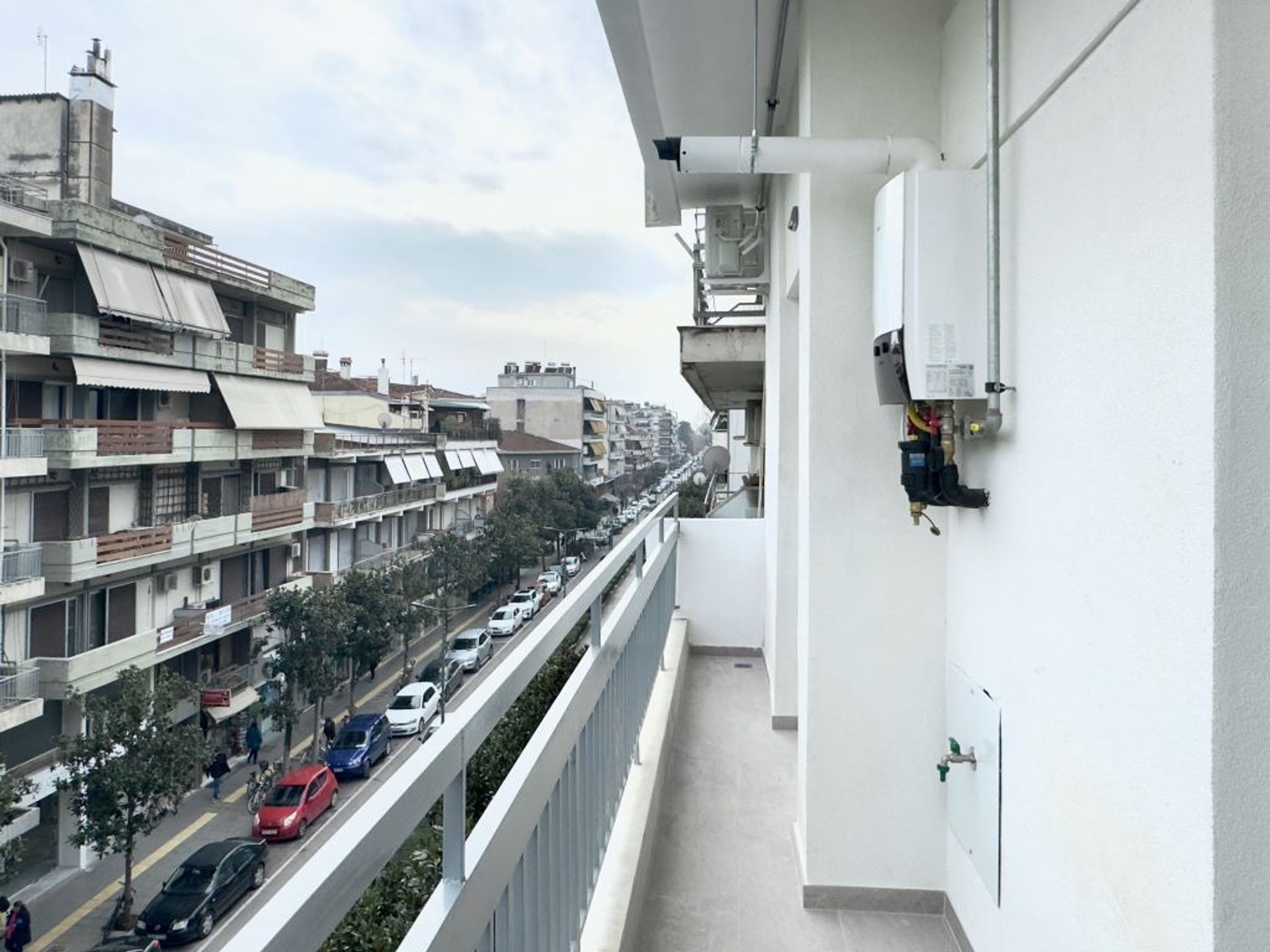 A balcony with a view of a busy street and multi-story buildings.