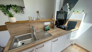 Ett modernt kök med en diskho i rostfritt stål, en bänkskiva i trä och ljusa skåp.