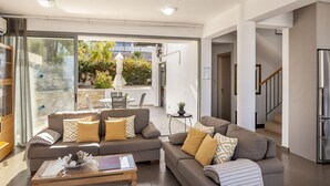 A modern living room with two sofas, a coffee table, and a glass door leading to an outdoor area. - Lenias Sea View in Neo Chorio (Neo Chorio)